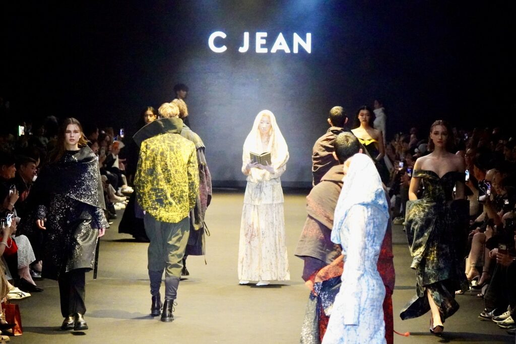 由文化部主辦之 26AW 臺北時裝週開幕秀新創舉，焦點模特兒手持《觀音菩薩普門品》，結合佛教文化音樂，以行動演繹走步，詮釋 「SA TA NA MA」 生命循環與佛學哲思意象。《觀音菩薩普門品》 為國立故宮博物院與僧伽林文化出版有限公司共同合作之國寶復刻經書。圖/楠西萬佛寺