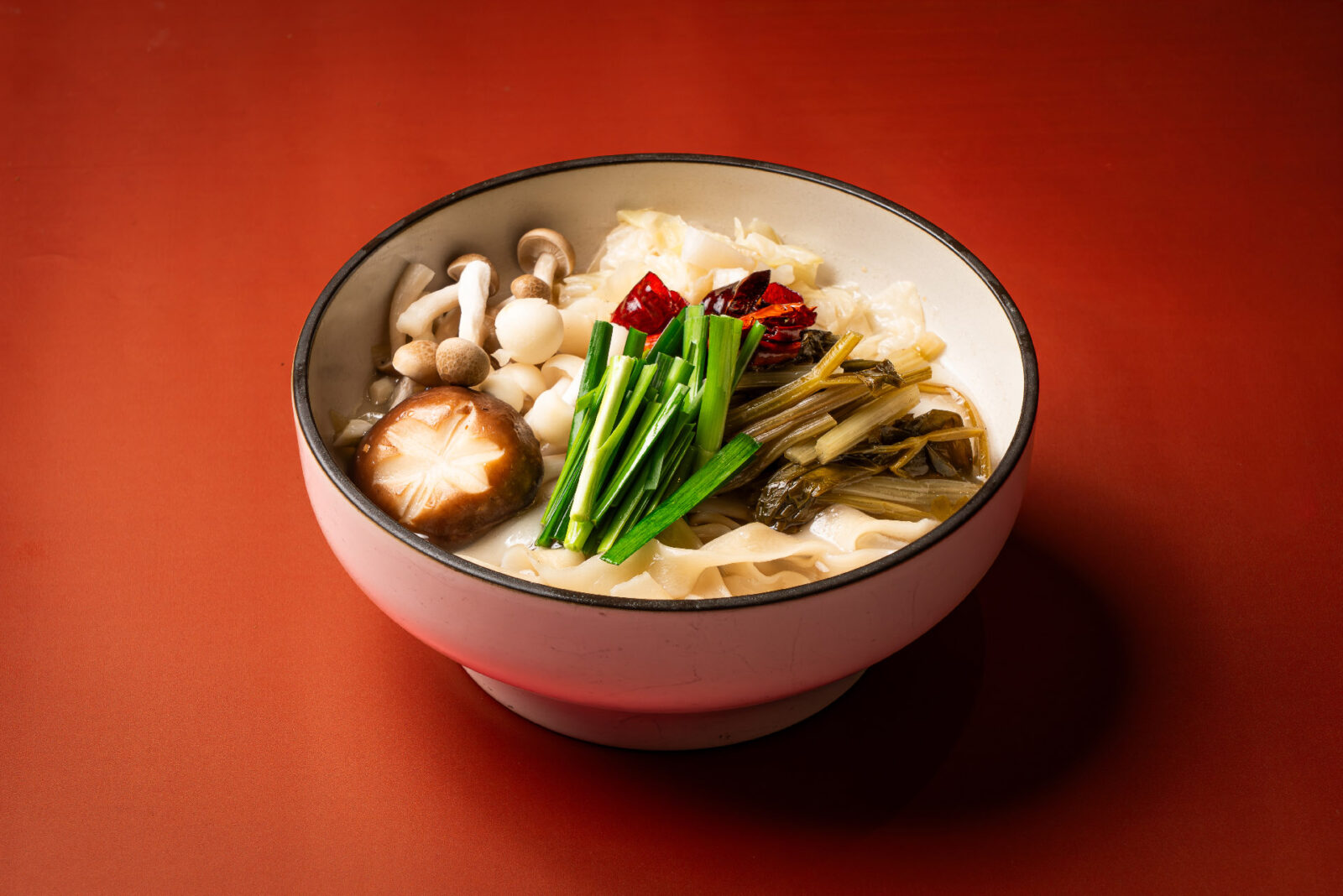 「秦香野菌漿水麵」以陝西傳統「漿水」為風味基底,將芹菜、高麗菜汆燙後加入麵湯發酵,形成自然微酸的清爽滋味,搭配野菌香氣,呈現不同於一般中式湯麵的風味層次。圖/板橋凱撒大飯店提供